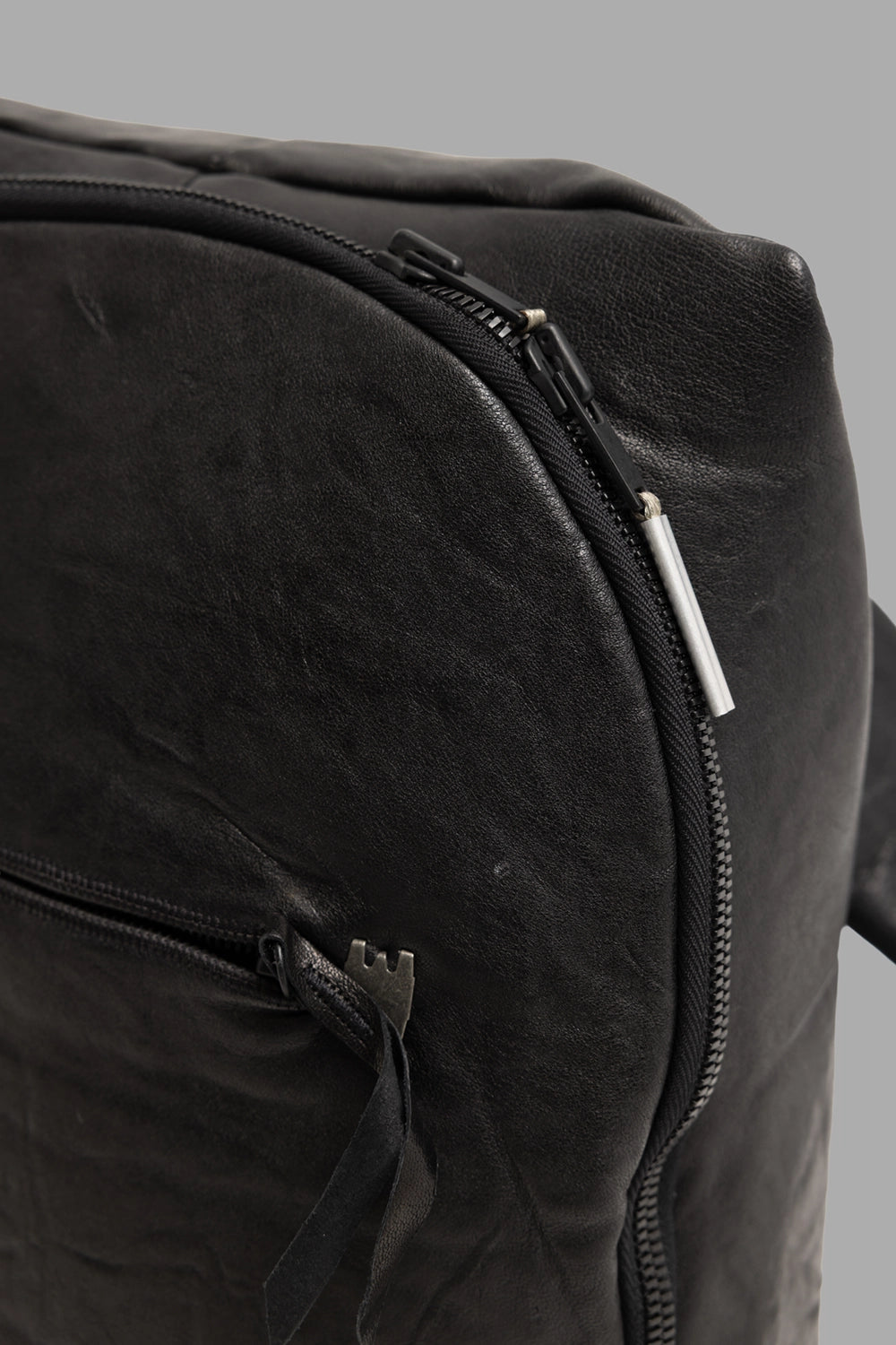 Isaac Sellam Experience unisex leather backpack in black, hardware close-up, metal spine zip and tubular pull.