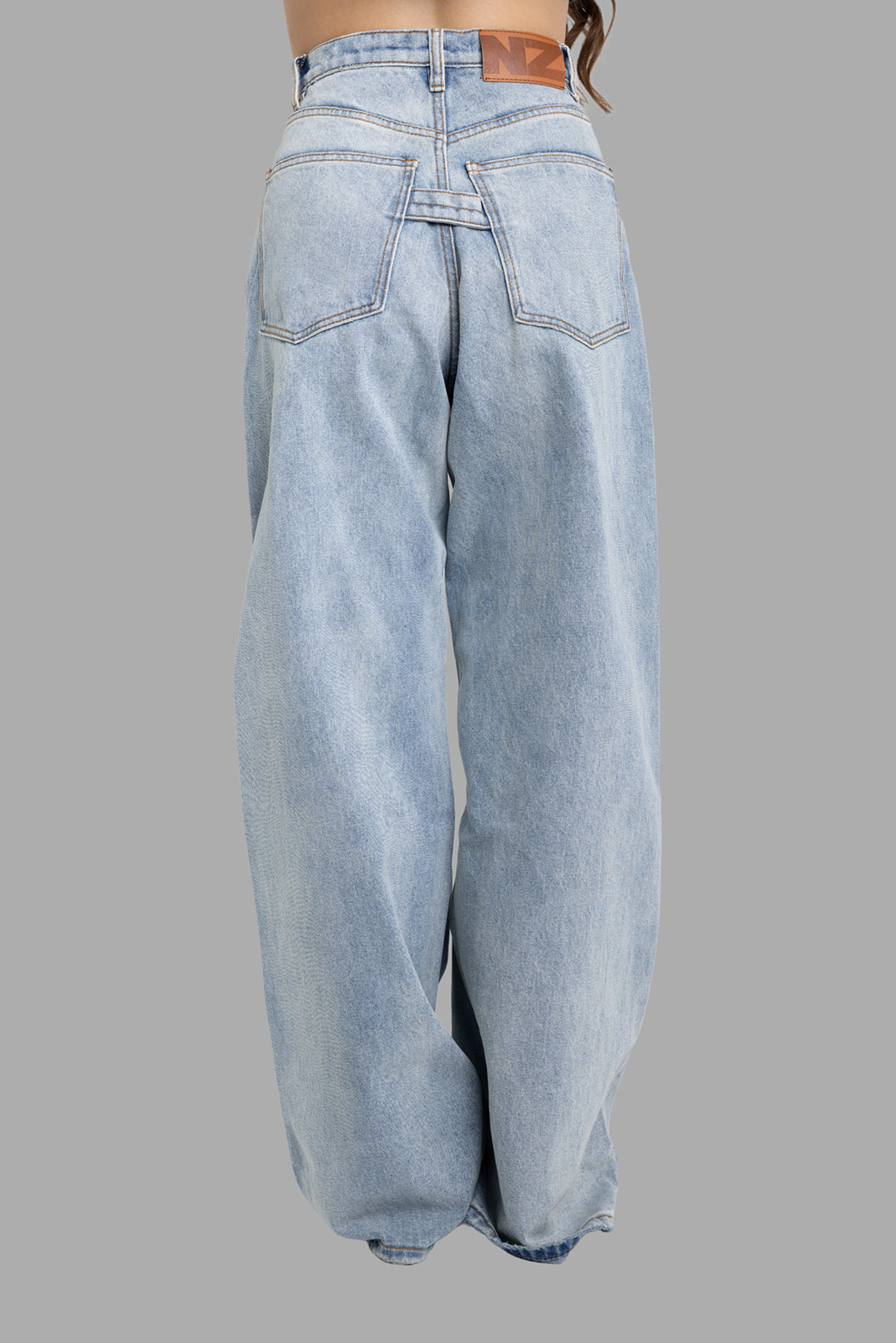 Natasha Zinko baggy jeans in light wash, back view with patch pockets, back strap and logo leather patch on waistband