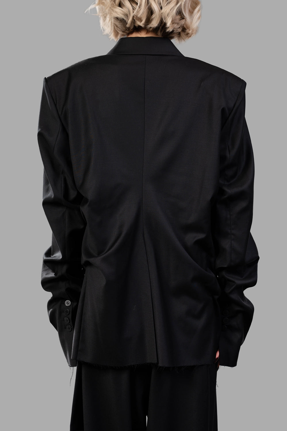 Natasha Zinko blazer in black wool‑blend, back view, raw‑edge hem and center back seam
