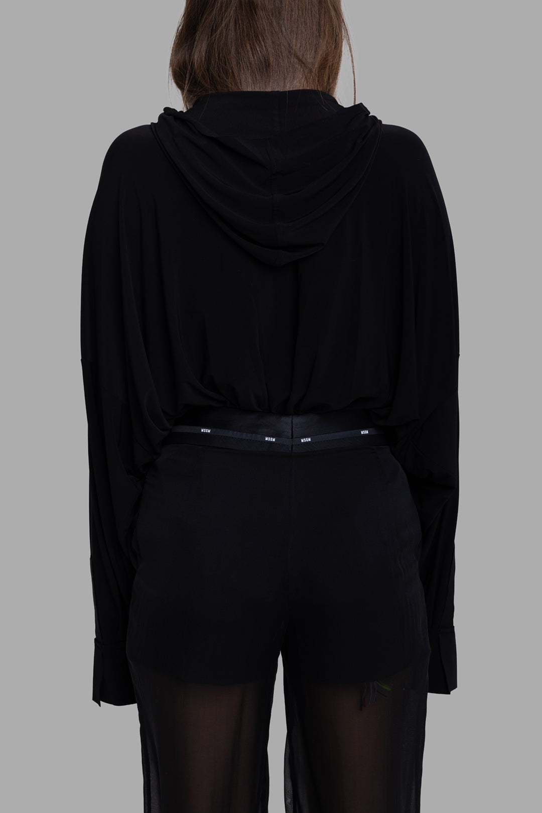Norma Kamali women’s black hooded bodysuit, back view with relaxed hood and blouson shirt silhouette