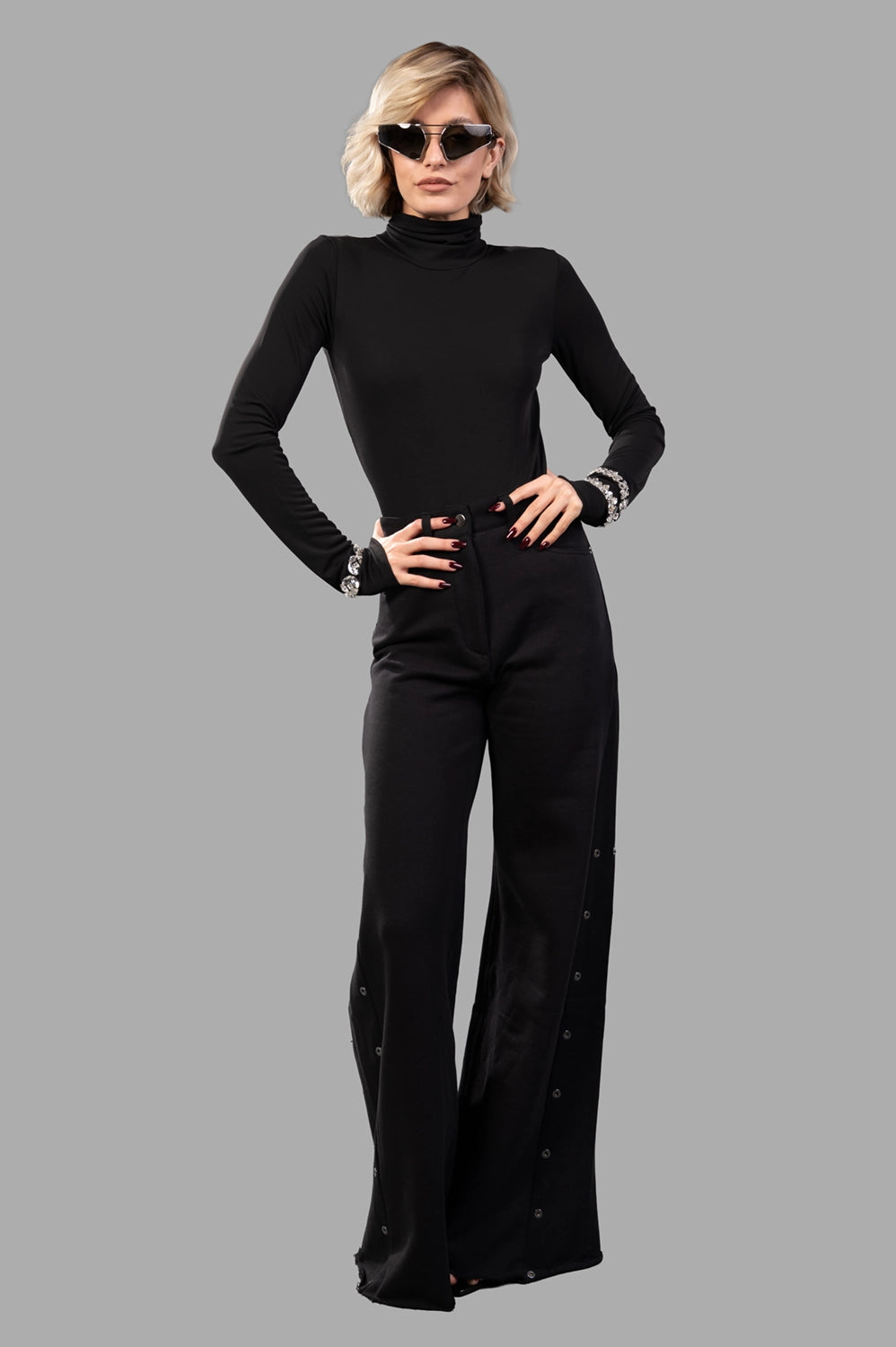 black high-neck bodysuit on model, full-length view, fluid jersey with crystal-embellished cuffs