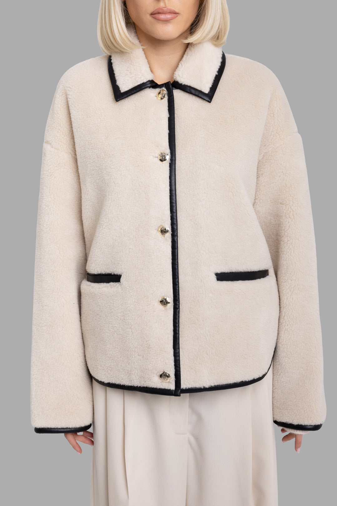Anine Bing women's cream Camden teddy jacket, front view highlighting gold buttons and black faux-leather trim pockets.