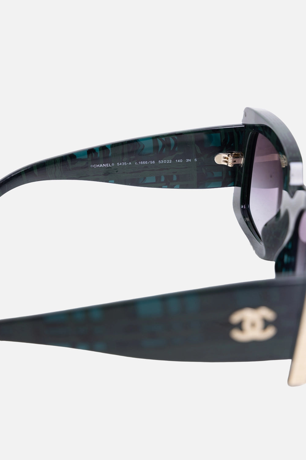 Side view of Chanel sunglasses showing gold-tone interlocking CC logo and metal temple detail