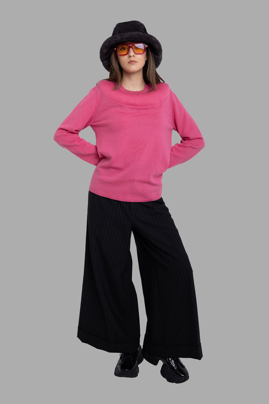 Comme des Garçons women's pink wool jumper, on-model full length, wide yoke neckline styled with pinstripe trousers.