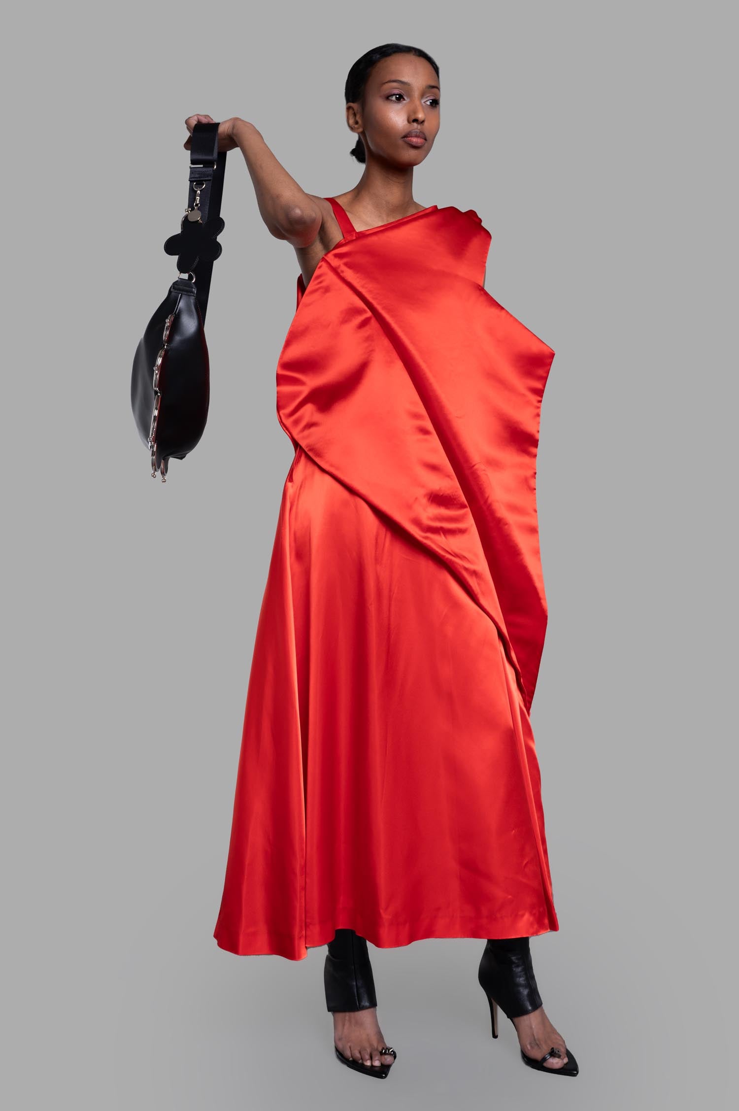 Noir Kei Ninomiya Asymmetric Dress in Red, front view on-model, with bold draping and black accessory.