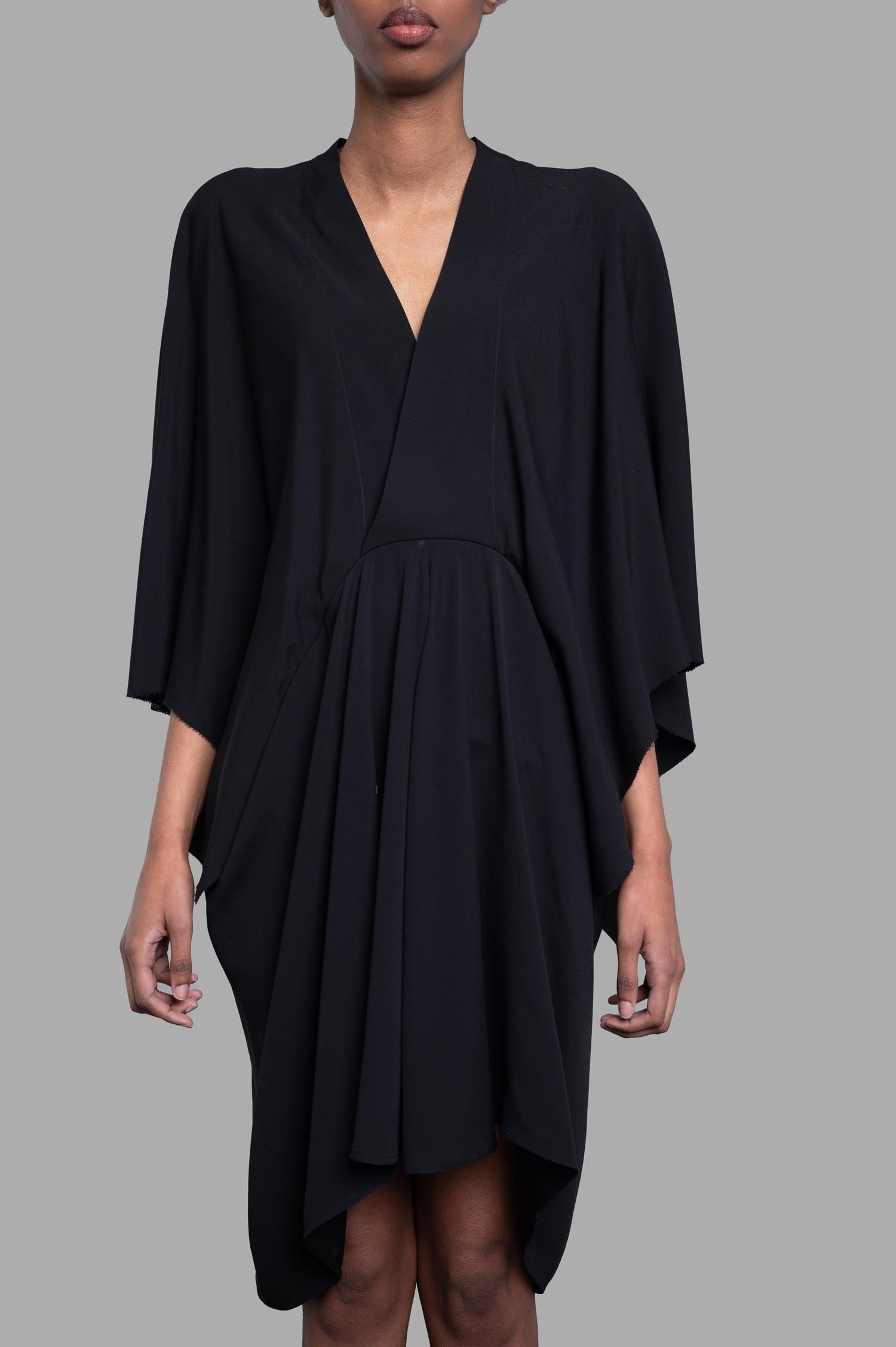 Rick Owens Half Moon Dress in black, featuring crossover neck and asymmetric sleeves, styled on model with high-low hem.