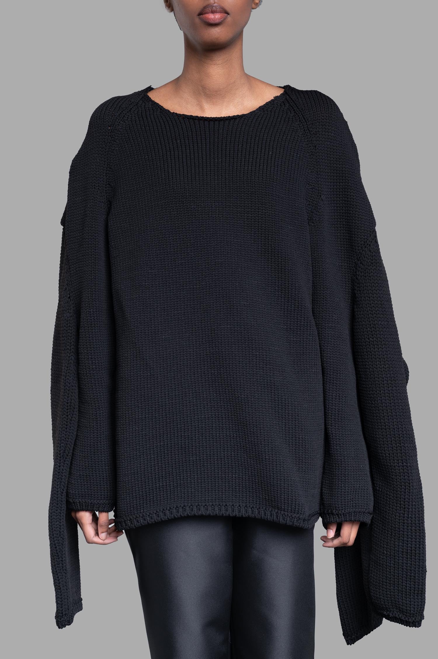 Comme des Garçons Multi-sleeve Sweater in black, highlighting its distinctive layered sleeve design on a fashion model.