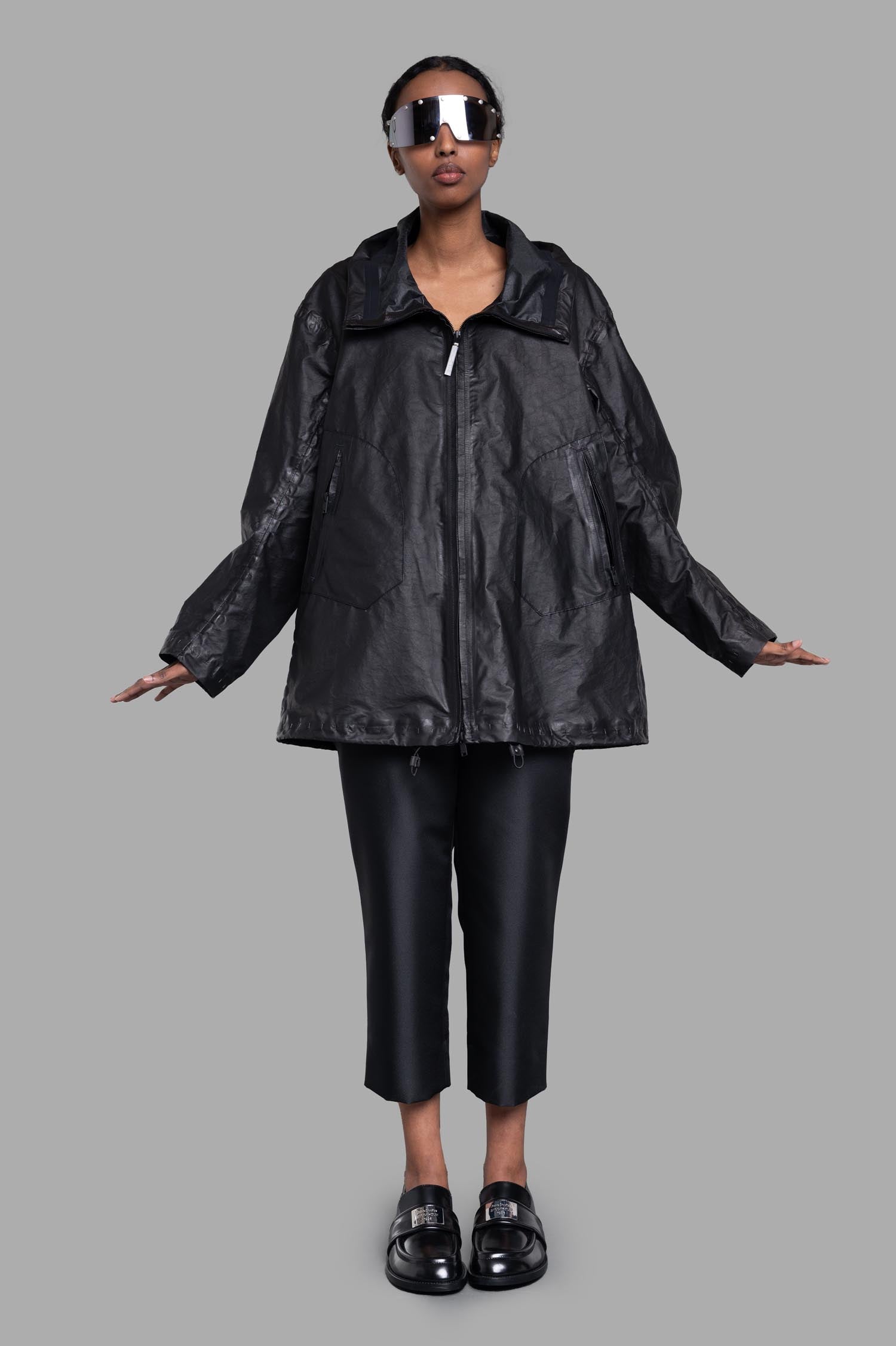 Isaac Sellam black oversized jacket front view with tube neckline and zipper, modeled with sunglasses, lambskin-organza.