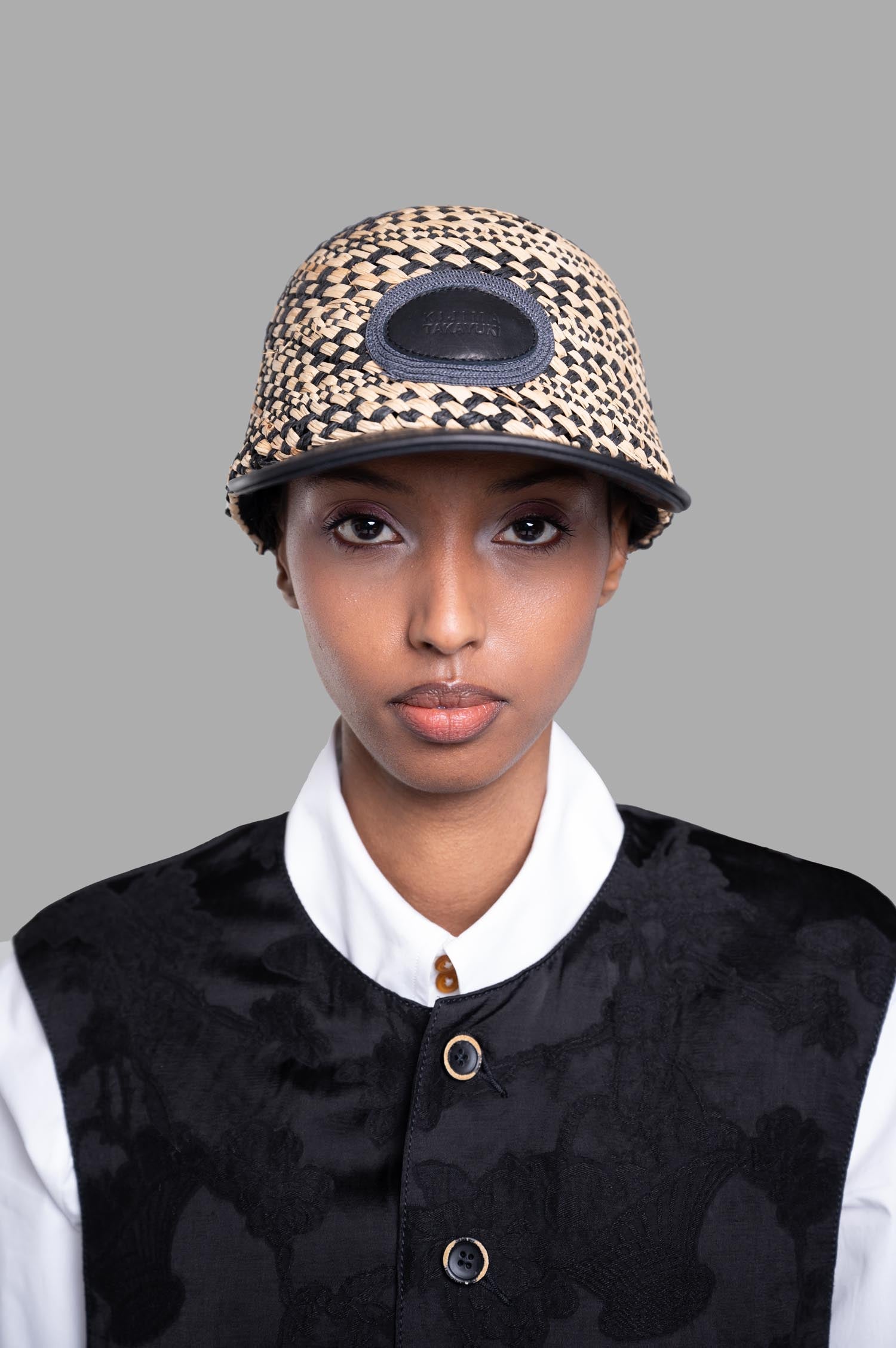 Kijima Takayuki Color-block Straw Hat displayed on a model, showcasing its elegant black and beige design and intricate texture.