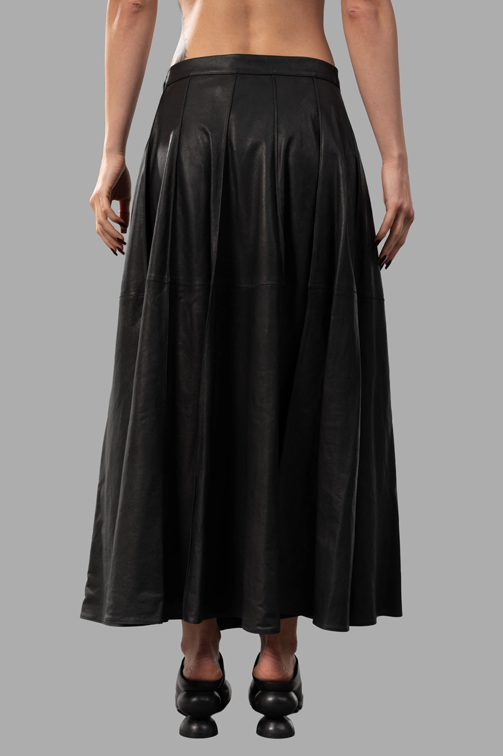 Back close-up of black leather skirt with panel seams and full A-line movement