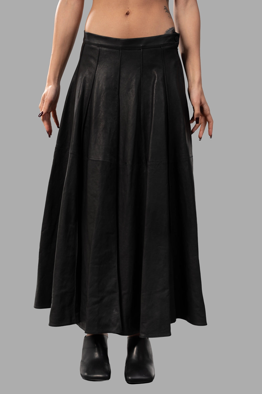 Front close-up of black leather skirt showing smooth waistband, side zip and vertical paneled seams