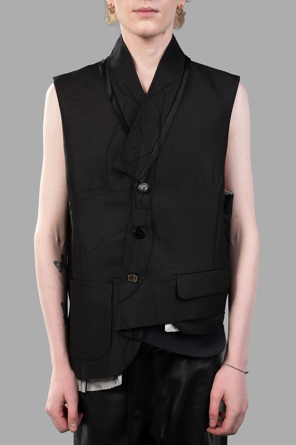 Front close-up showing draped shawl collar, mixed buttons, flap pockets, raw-edge hem