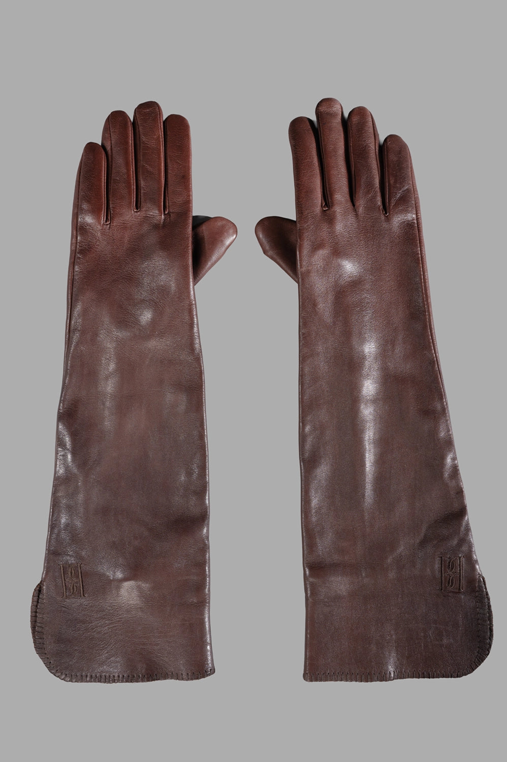 Pair of long brown leather gloves with extended cuffs and smooth finish, front view