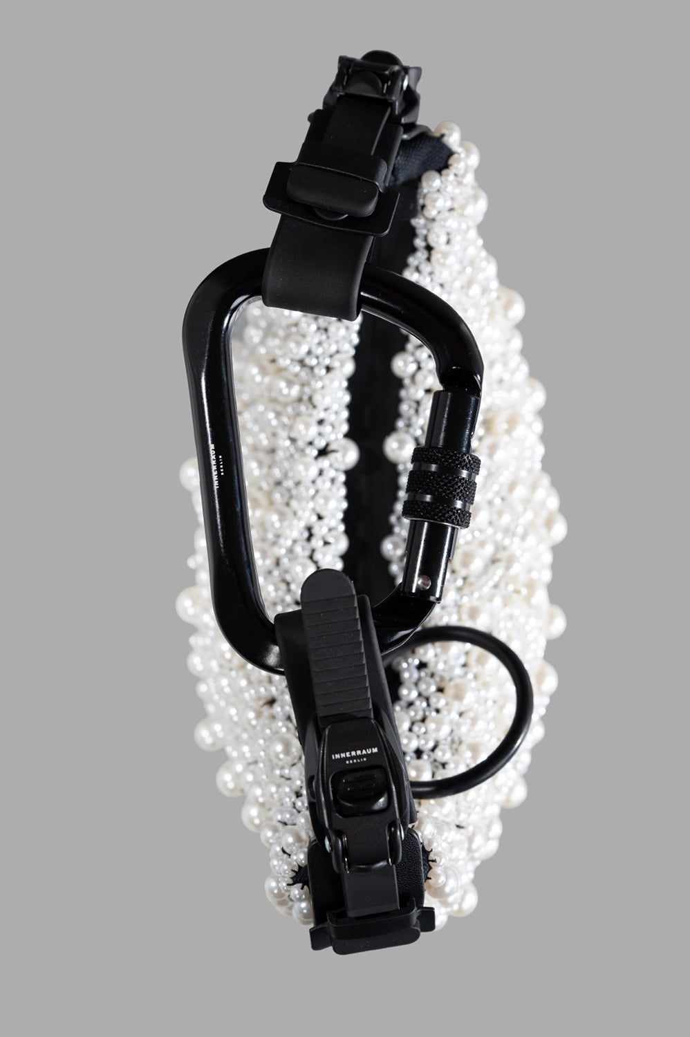 Front close-up of pearl beaded surface with half-moon curve, black matte strap and zip.