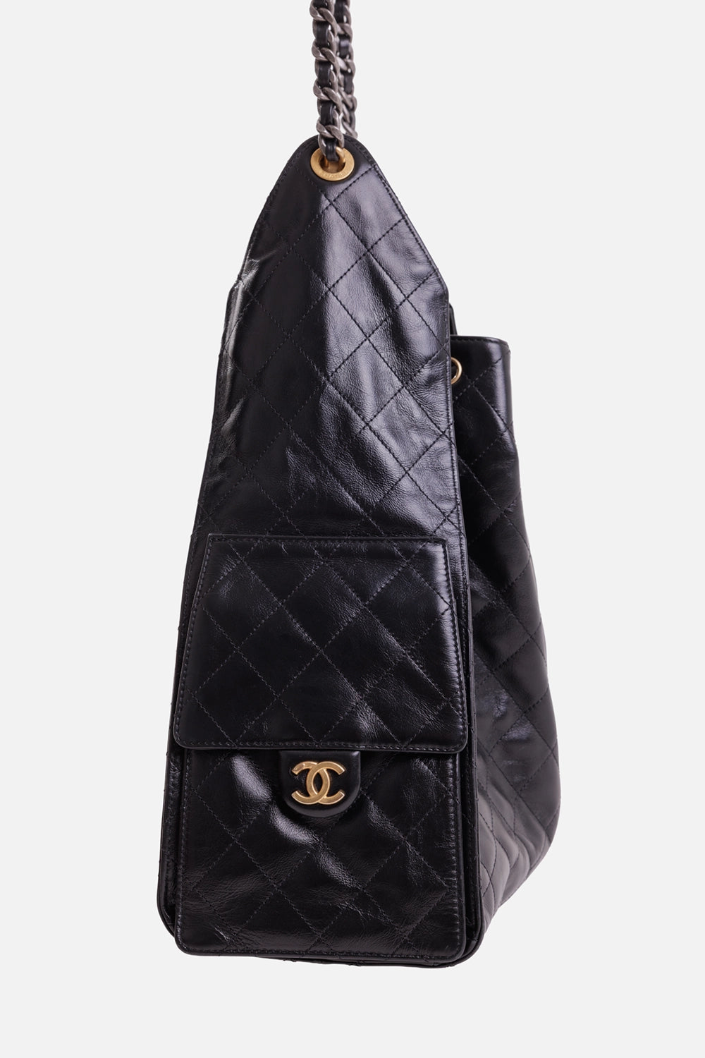 Chanel women's black calfskin hobo bag, side view with quilted flap pocket, gold-tone CC and ruthenium chain