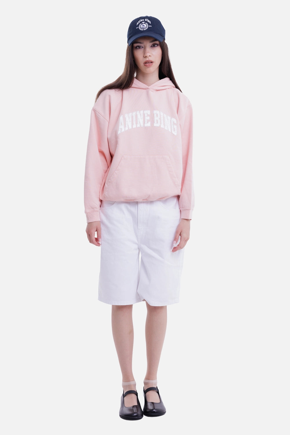 Anine Bing women's coral pink hoodie, on-model view with white collegiate chest logo and kangaroo pocket