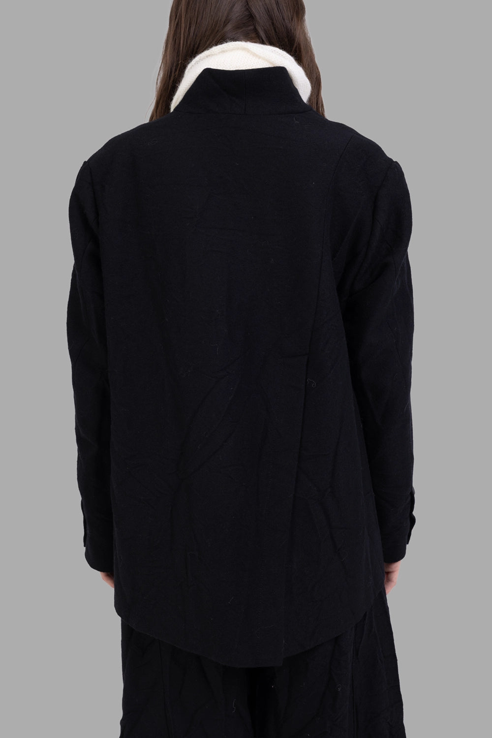 Marc Point women’s black jacket, back view, long curved hem and single back vent, crinkled wool surface.