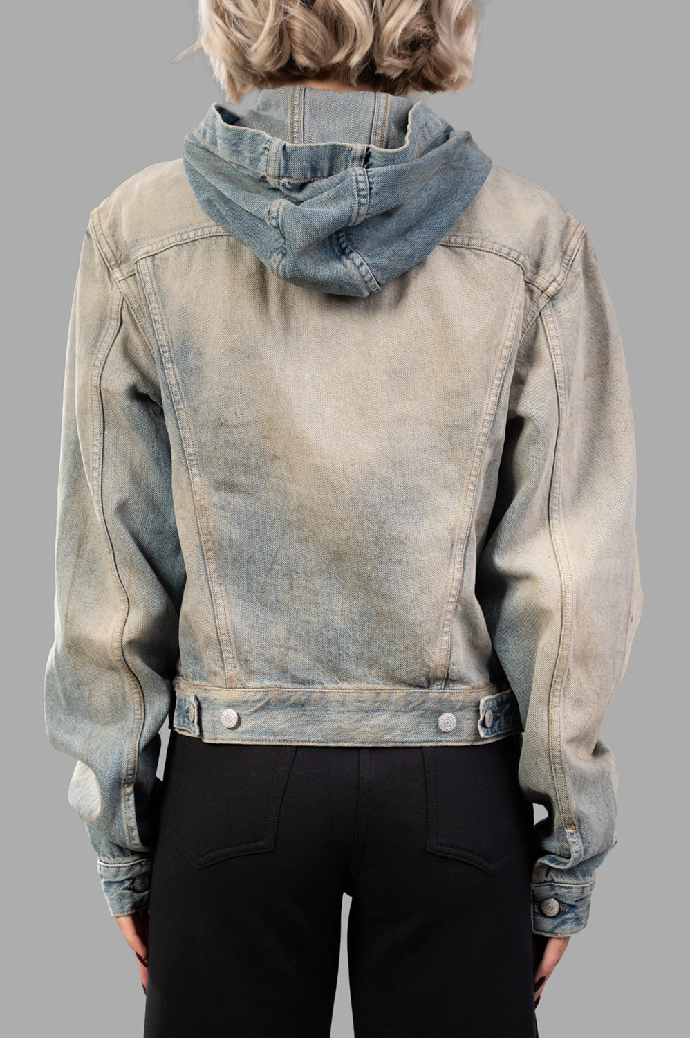 Back close-up of hooded denim jacket with V-yoke, adjustable hem tabs and distressed finish