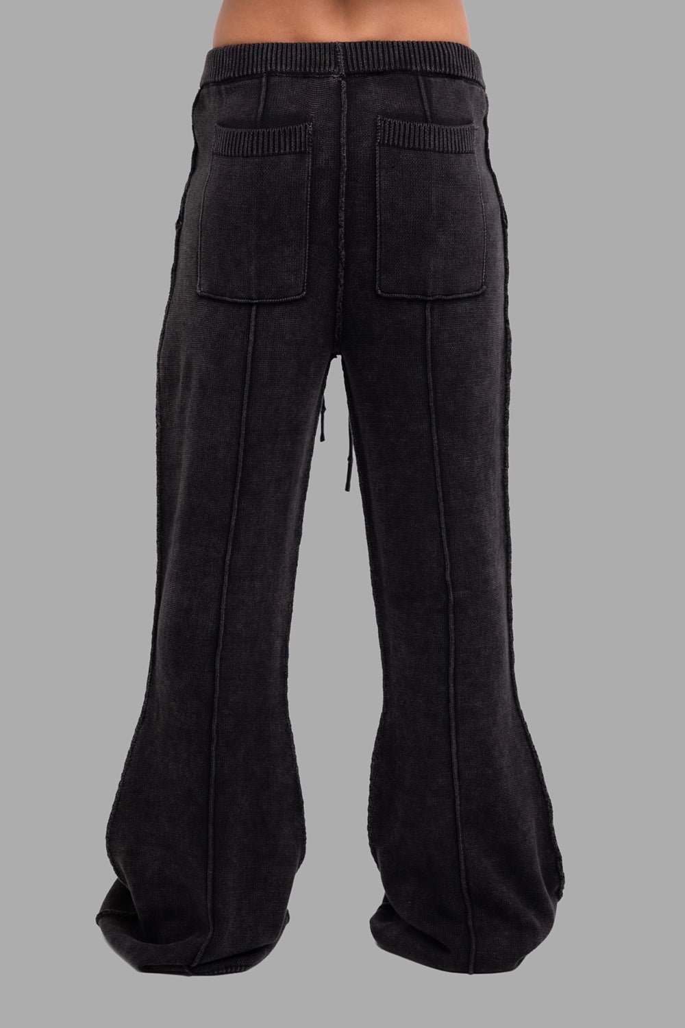 Justin Gall men’s knit pants in black, back view, patch pockets and extended cuff hem.