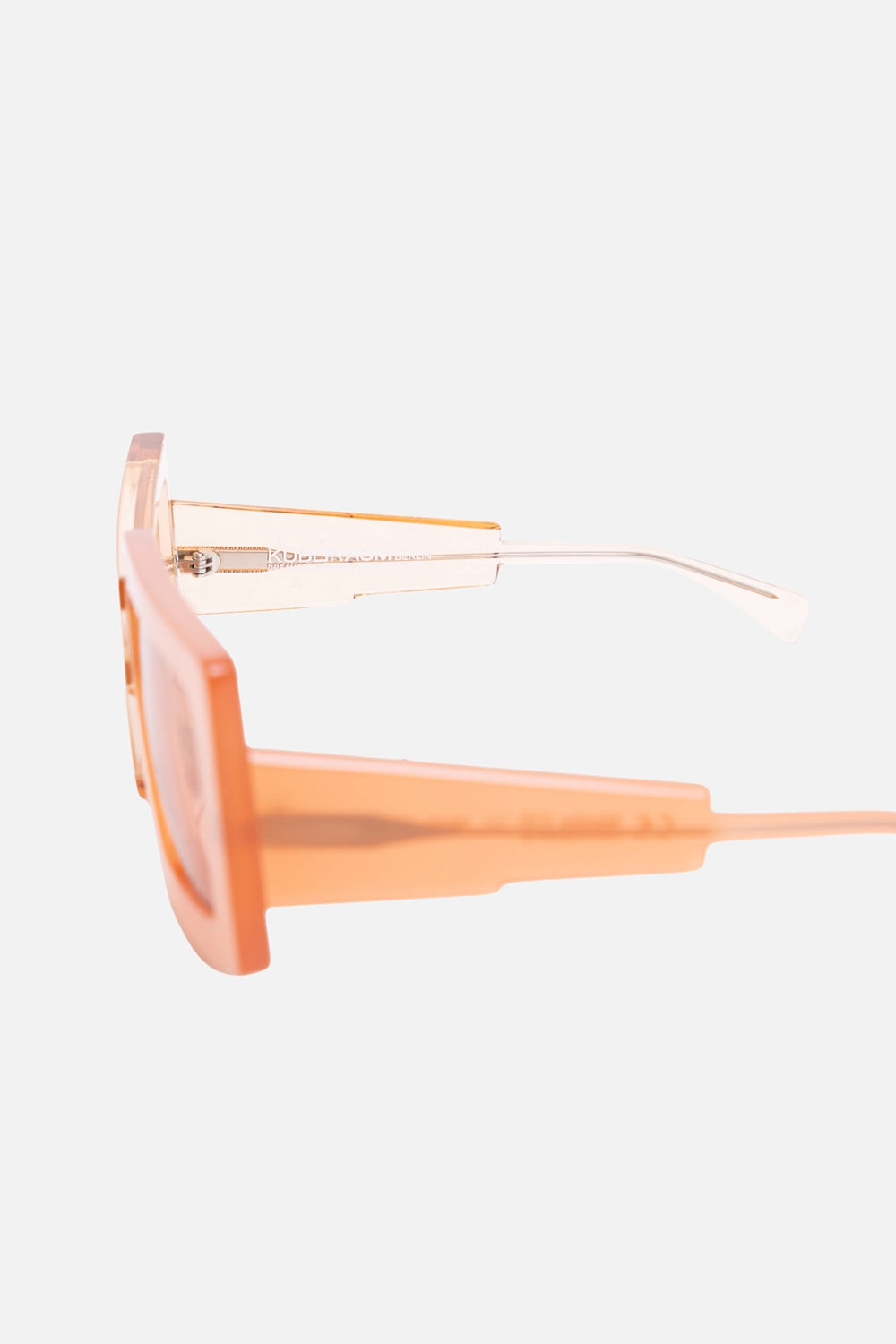 Close-up of Kuboraum sunglasses temple with logo detail and translucent peach arm