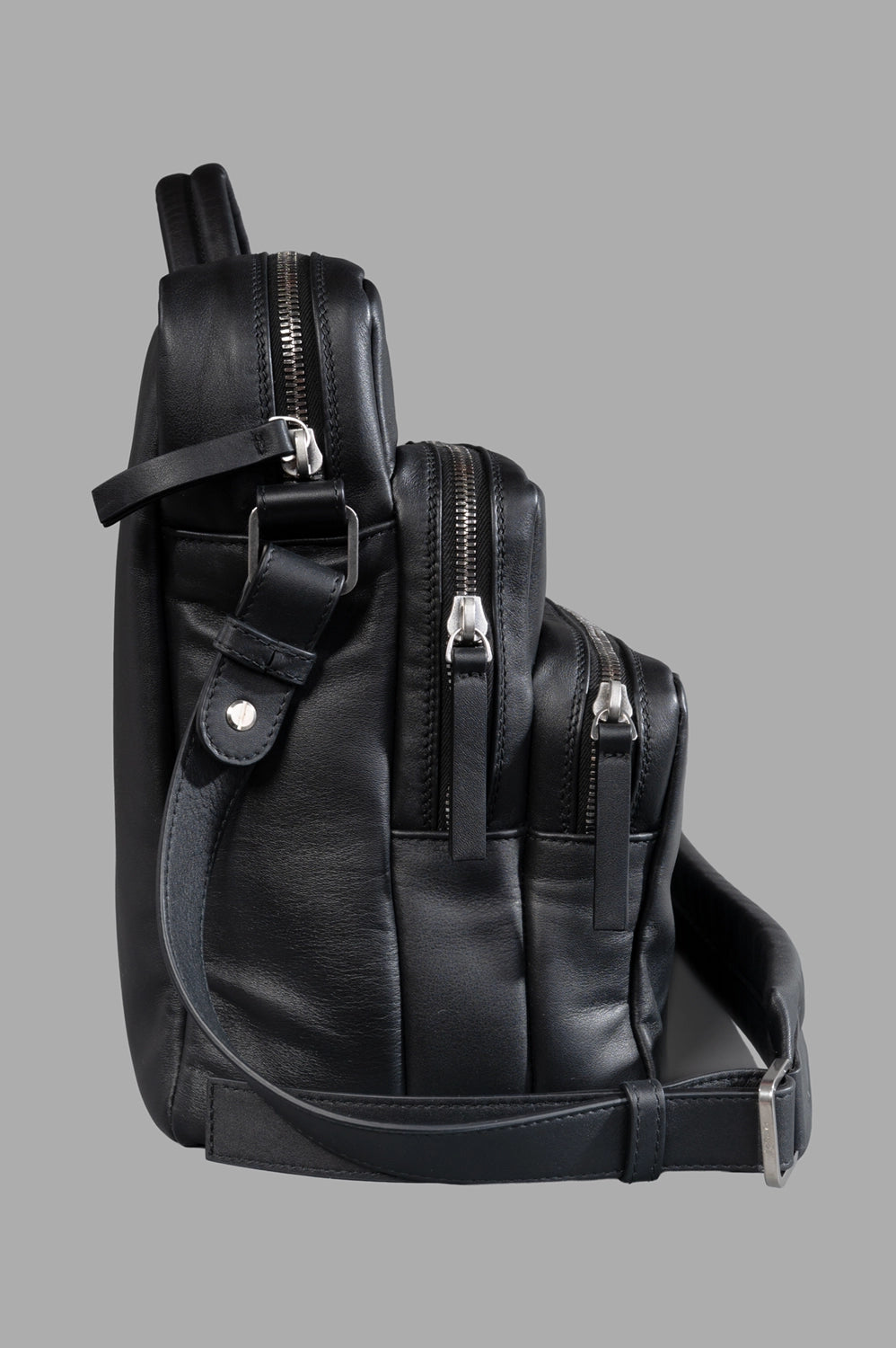 Marsèll laptop bag in black, side view, tiered profile with silver zips and strap