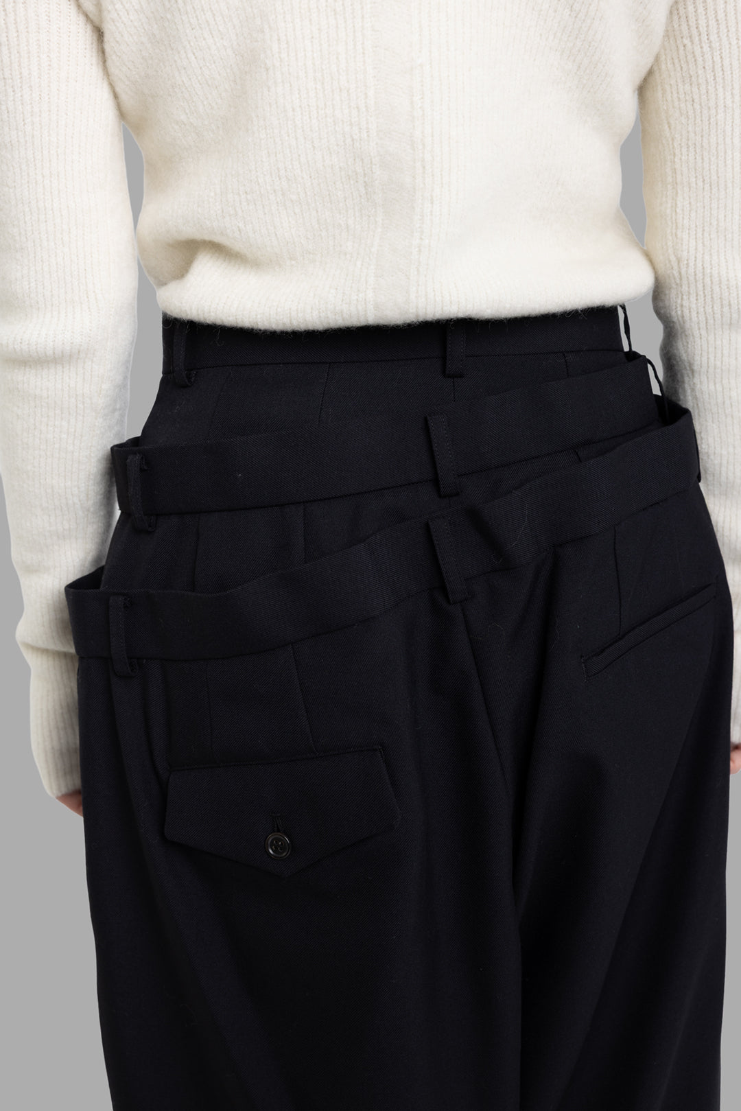 Noir Kei Ninomiya black layered waist trousers, back waistband detail showing stacked belt layers and welt pocket