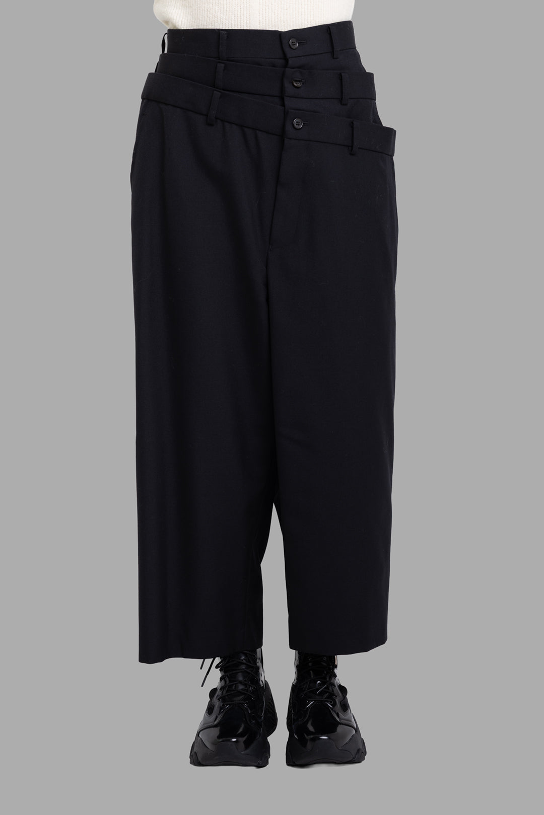 Noir Kei Ninomiya black layered waist trousers, front view showing high-rise fit and smooth wool-blend cropped leg