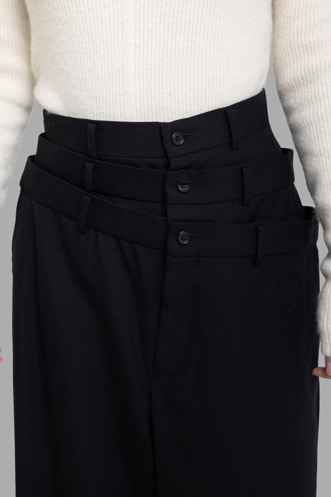 Noir Kei Ninomiya black layered waist trousers, close-up front waistband with three overlapping belt bands and buttons