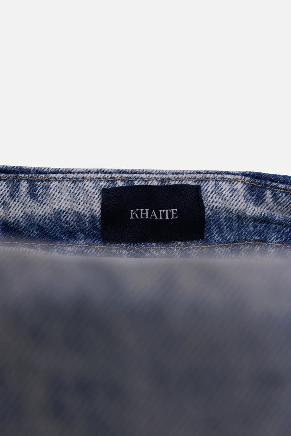 Khaite women's denim midi skirt in blue, label detail with black tag and washed denim waistband