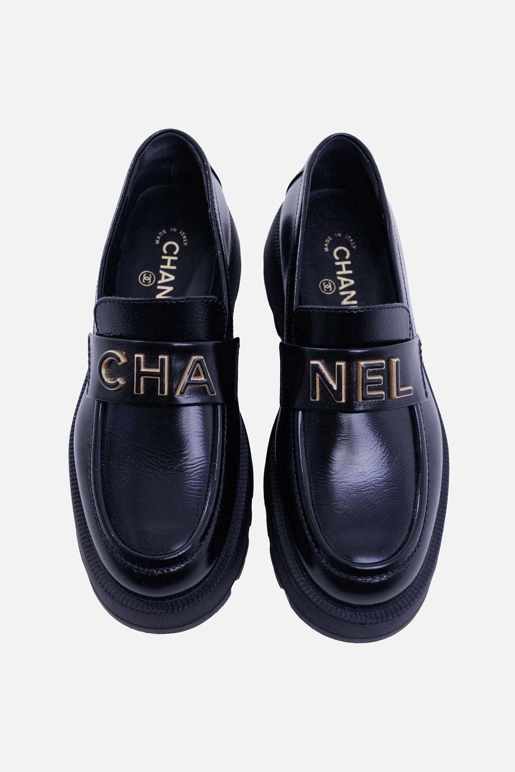 Chanel women's black leather loafers, top view with split CHA/NEL lettering and rounded apron toes
