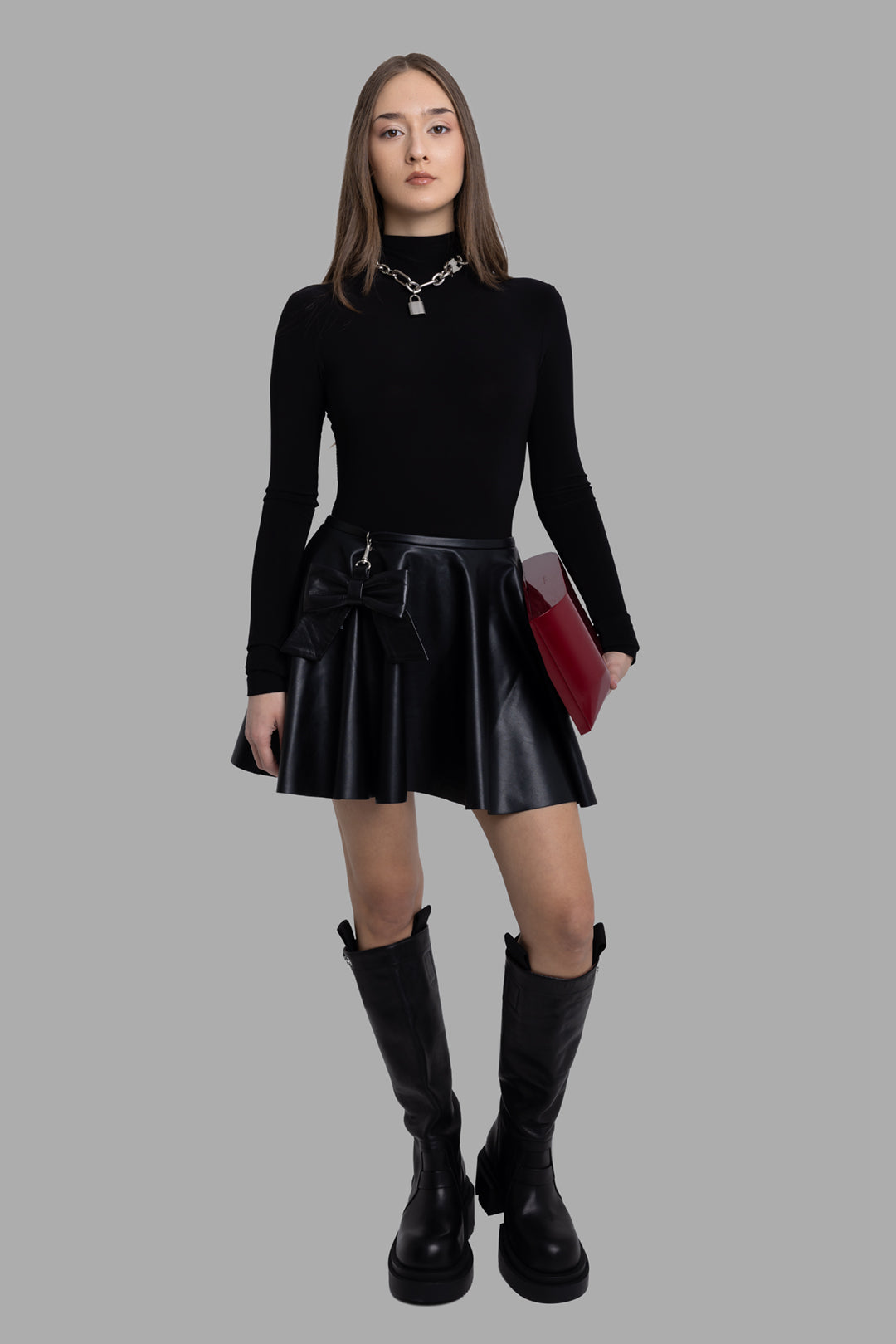 Norma Kamali women's black long sleeve turtleneck bodysuit, full-length front view on model styled with skirt and boots.