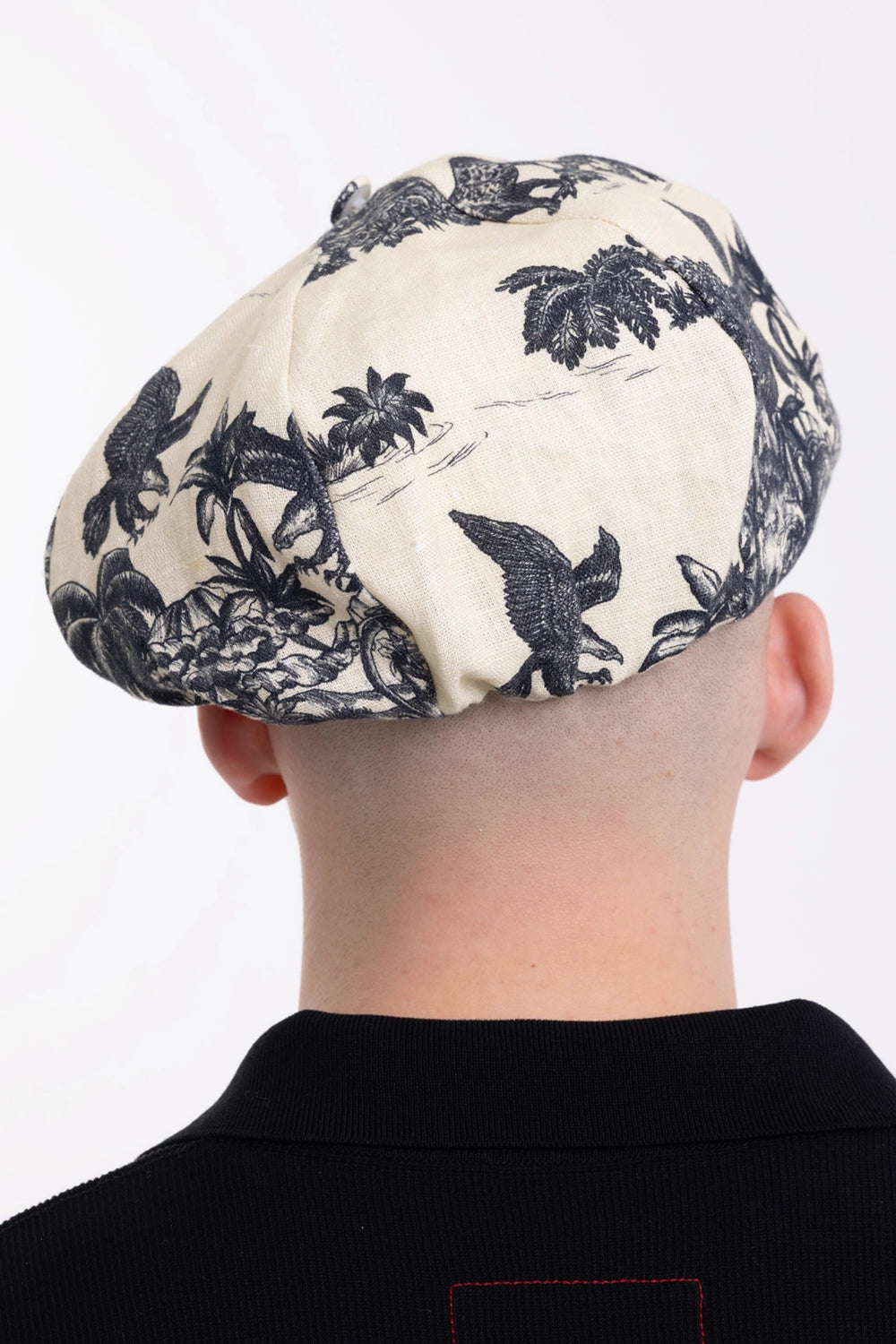 Marc Point men's newsboy cap in natural/black, back view with paneled crown, bird motif and palm tree print