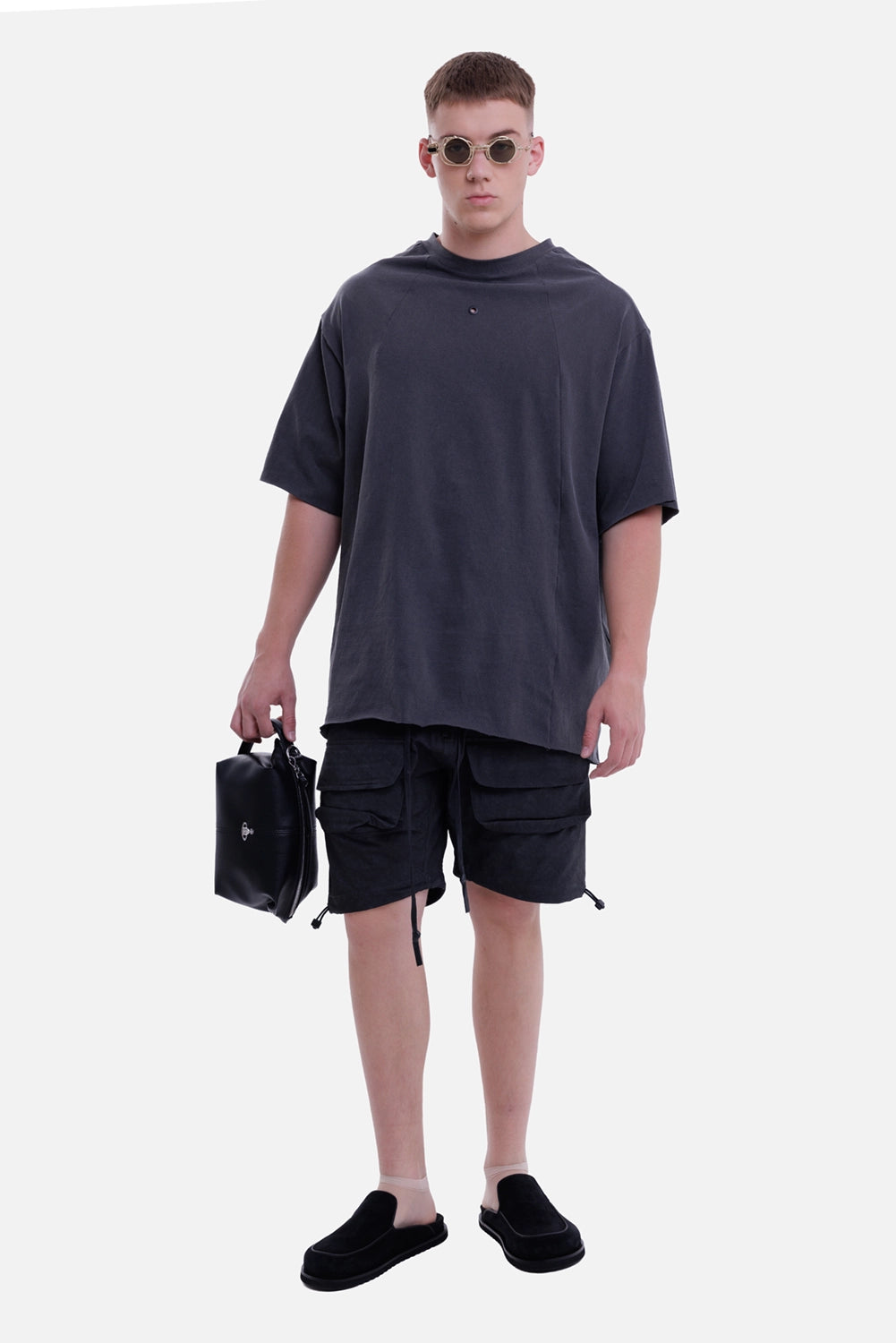 Justin Gall men's over tee in black, full-length on-model view styled with cargo shorts and leather bag