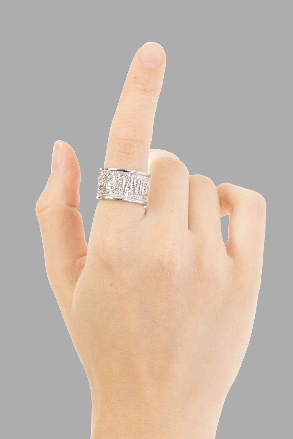 Vivienne Westwood women ring in platinum, on-model hand view, wide band with pavé crystals and raised logo.