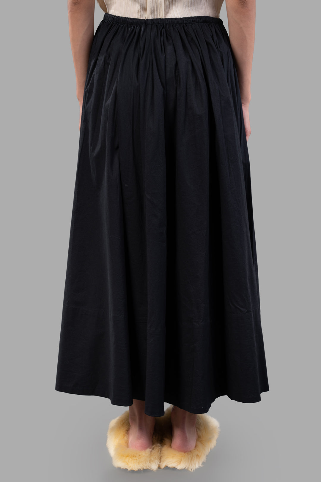By Malene Birger Pheobes Cotton Skirt in black, highlighting its soft flow and high-waist detail from a side perspective on.