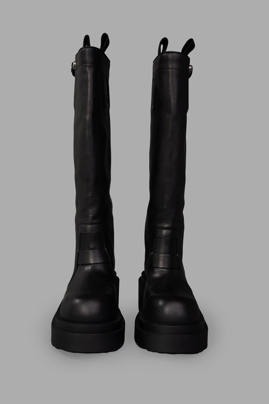 Rick Owens Bogun Knee-high Boots shown from the front, featuring sleek black leather and sturdy soles for a bold look.