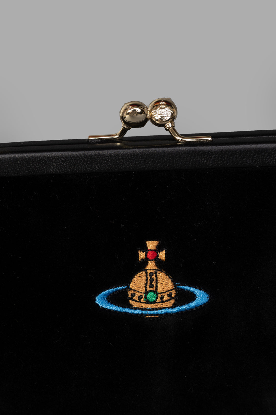 Vivienne Westwood Velvet Clutch features a vintage-inspired clasp and intricate embroidered logo on rich black velvet.