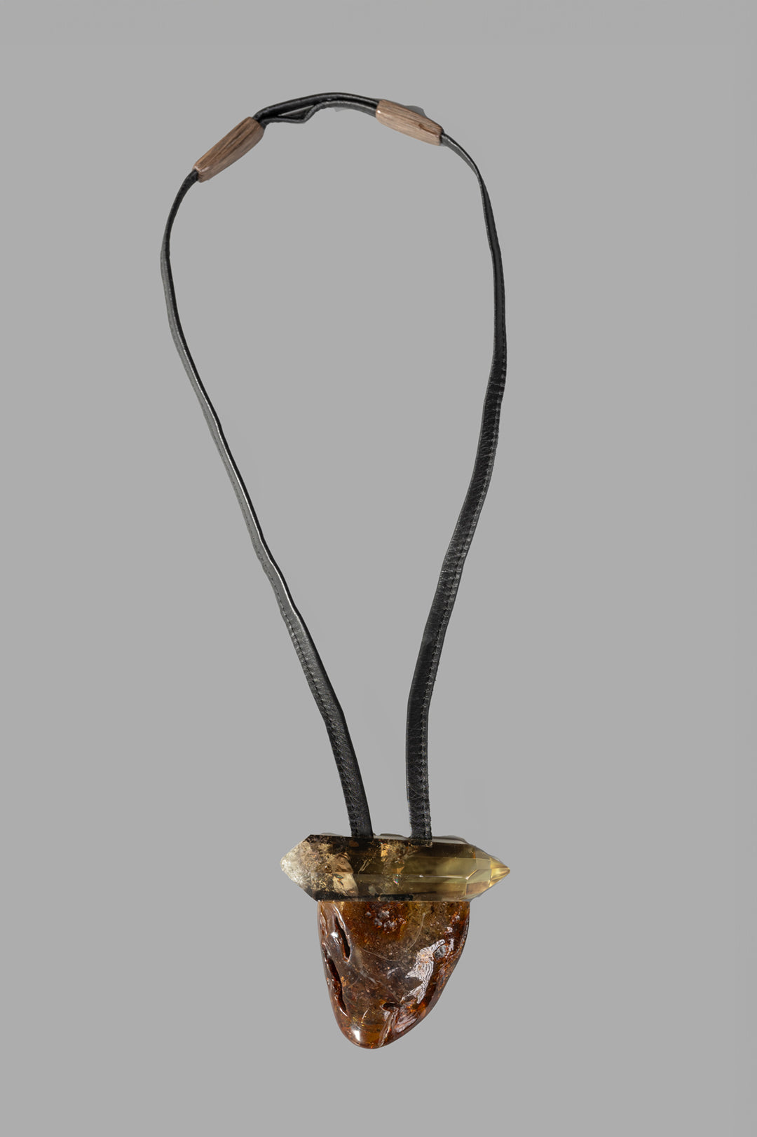 Monies Pendant Necklace features a large amber and citrine stone pendant on a black leather strap, showcasing front detail.