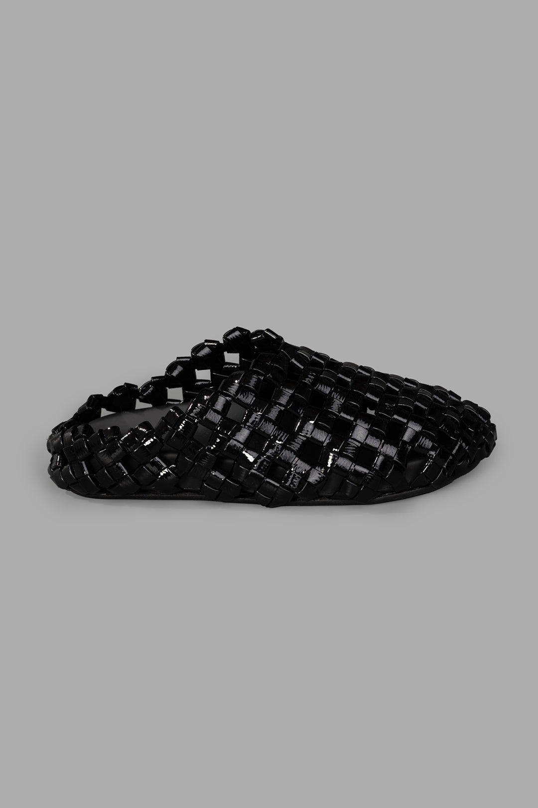 A.W.A.K.E. MODE Weaved Clogs in black leather. Side view showcasing woven slip-on design with chic, textured finish.