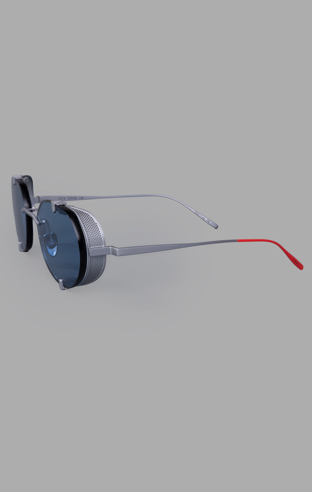 Vysen Eyewear The Uttar - UT4 showcases a side view of rimless titanium round frames with clear blue lenses and red accents.