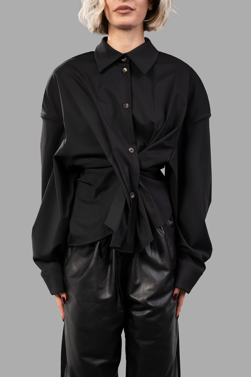 Front close-up of black twisted shirt showing spread collar, buttons and wrap detail that cinches the waist