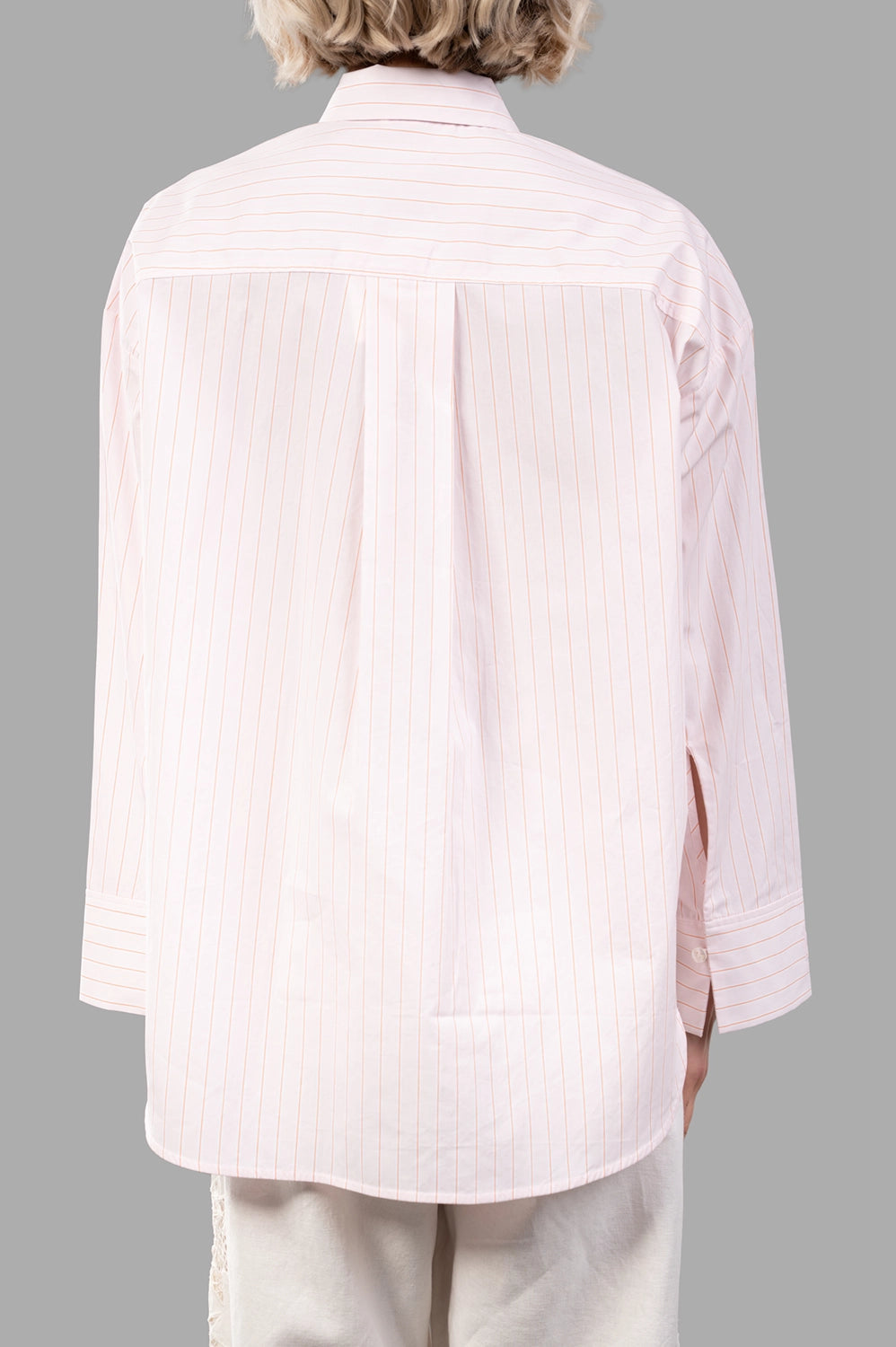 Back view of pink pinstripe shirt with yoke, box pleat and curved hem