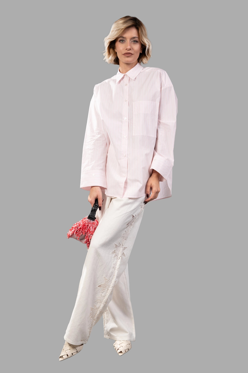 Full-length view of oversized pink pinstripe cotton shirt with chest pocket and wide cuffs