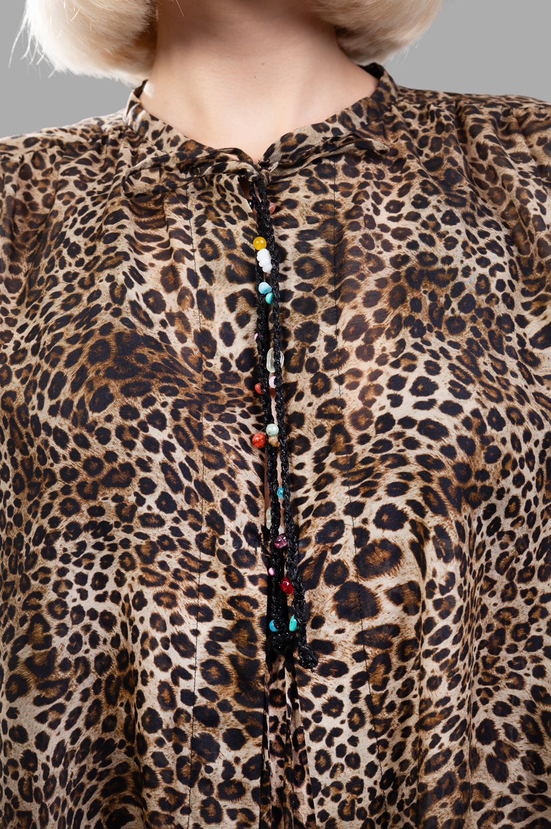 Anjuna Leopard Cape close-up showing intricate beaded tie closure and elegant leopard print texture.