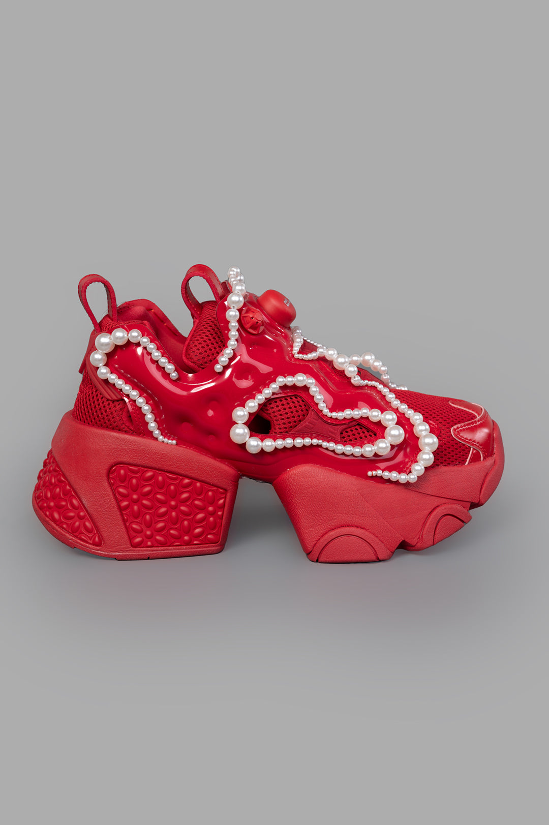 Noir Kei Ninomiya x Reebok red sneakers with pearl embellishments, side view. Features chunky sole and textured detailing.