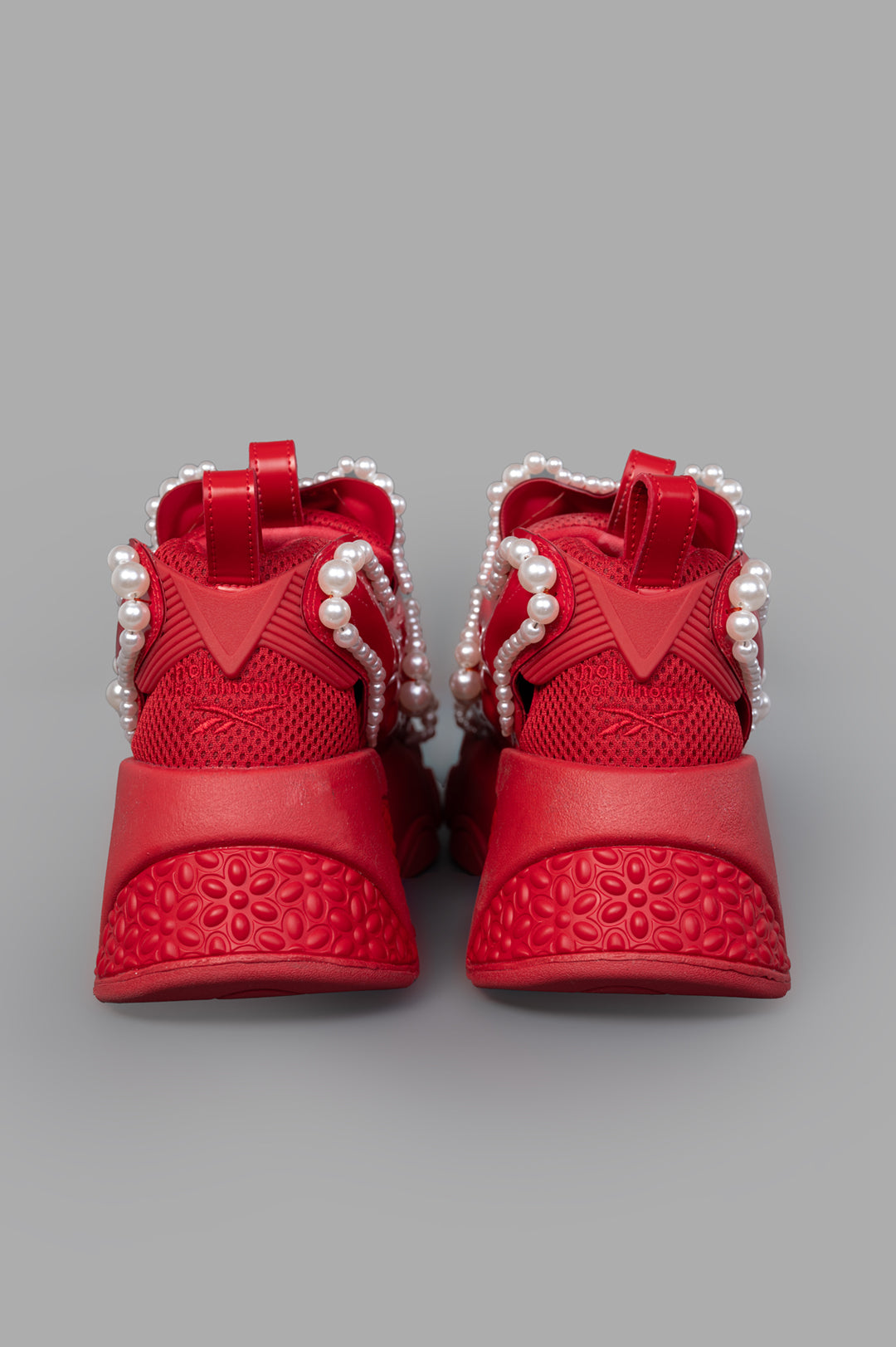 Noir Kei Ninomiya x Reebok red sneakers highlighting the vibrant front design adorned with striking pearl embellishments.