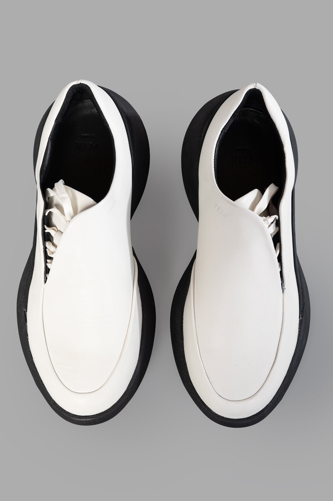Vein. Top view of black and white leather platform sneakers showcasing sleek design and minimalist silhouette.