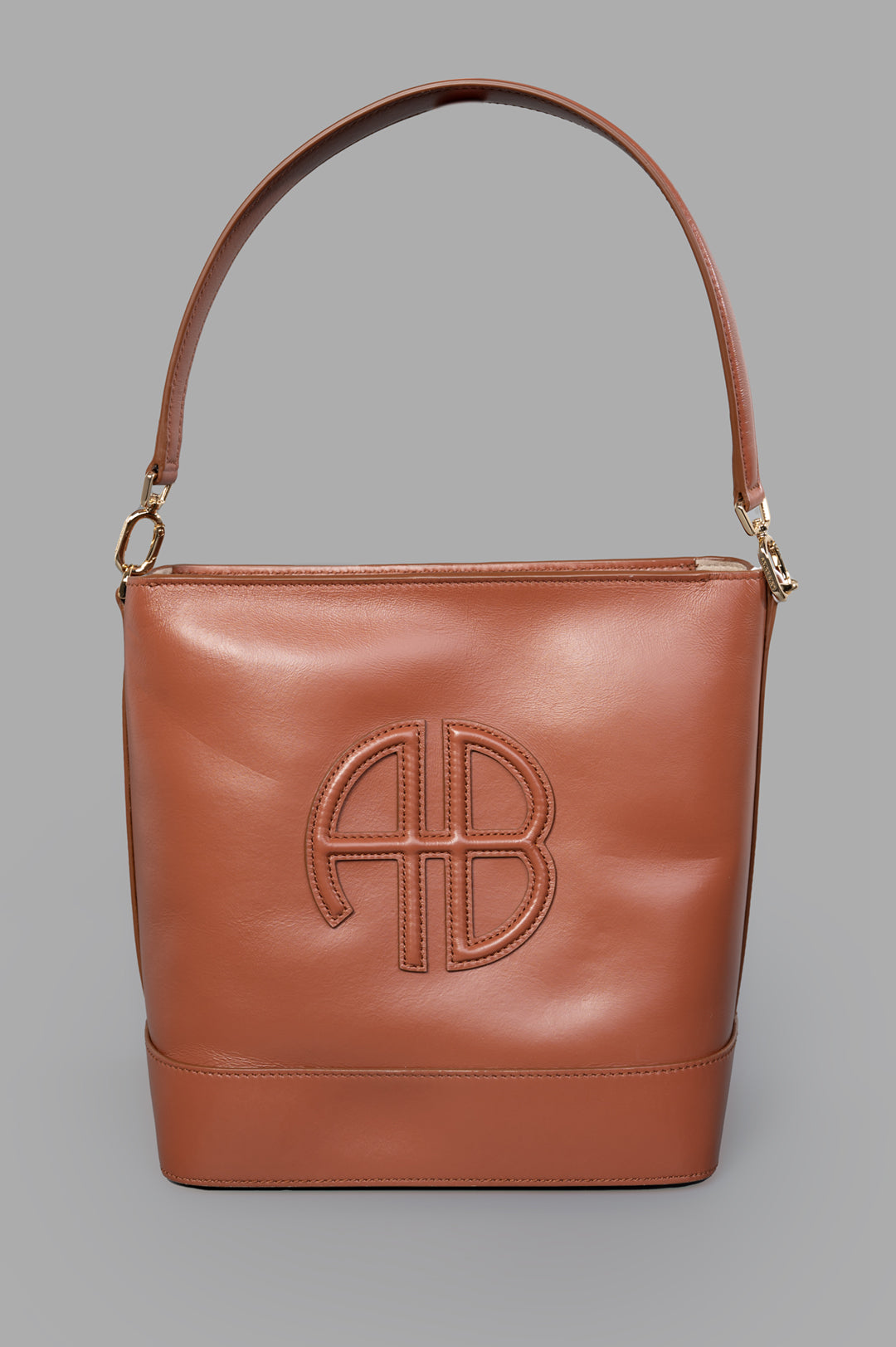 Anine Bing Lili Bucket Bag in cognac leather, front view with padded leather patch, gold hardware, and shoulder strap.