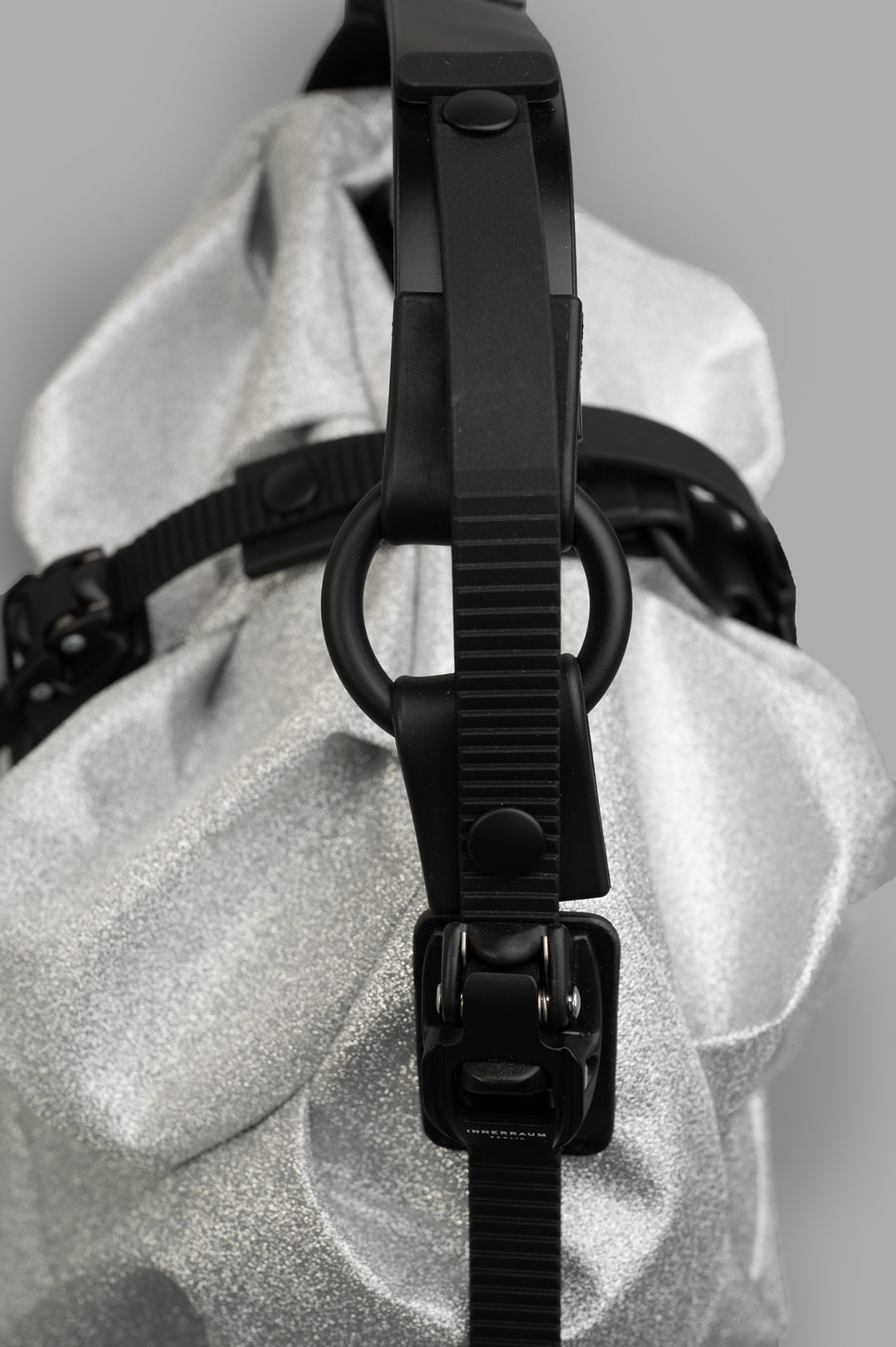 Innerraum. Silver Bag I96 close-up highlighting the adjustable black strap and textured silver material. Bold and modern.
