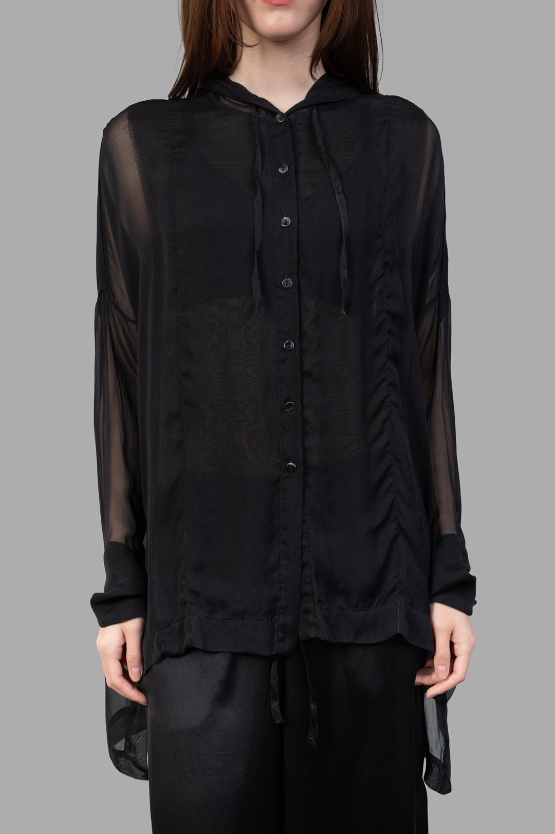 Masnada Hooded Shirt in black, featuring a translucent design, button closure, and drawstring hem, worn on a model.
